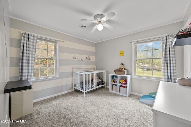 bedroom featuring a nursery area, baseboards, visible vents, ceiling fan, and carpet