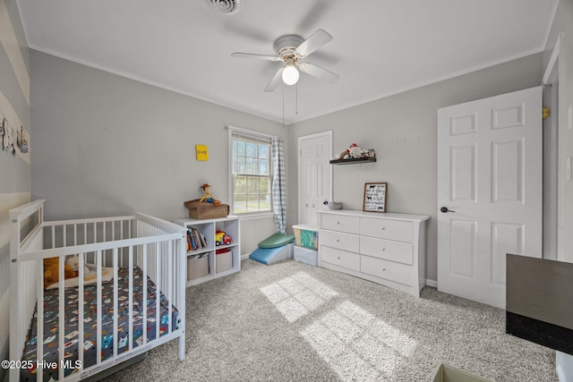 bedroom with a closet, crown molding, carpet flooring, a nursery area, and ceiling fan