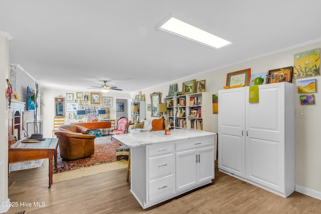 kitchen with light wood finished floors, white cabinetry, a ceiling fan, and ornamental molding