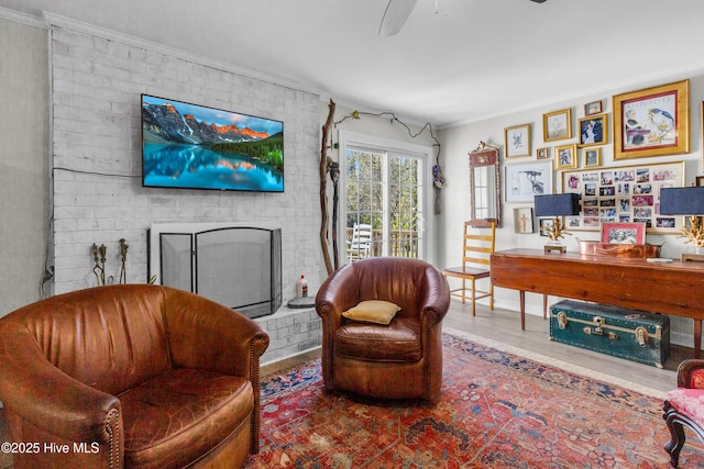 living area featuring ornamental molding, a ceiling fan, wood finished floors, and a fireplace