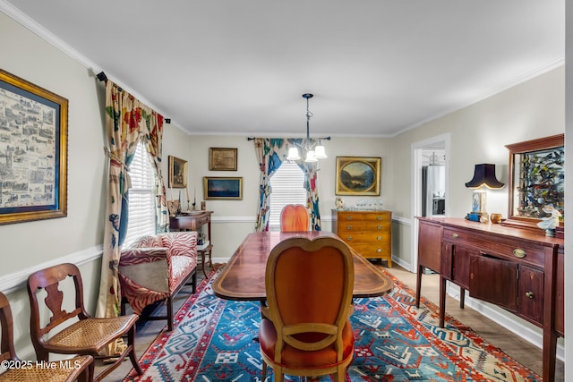 dining space featuring baseboards, an inviting chandelier, ornamental molding, and wood finished floors