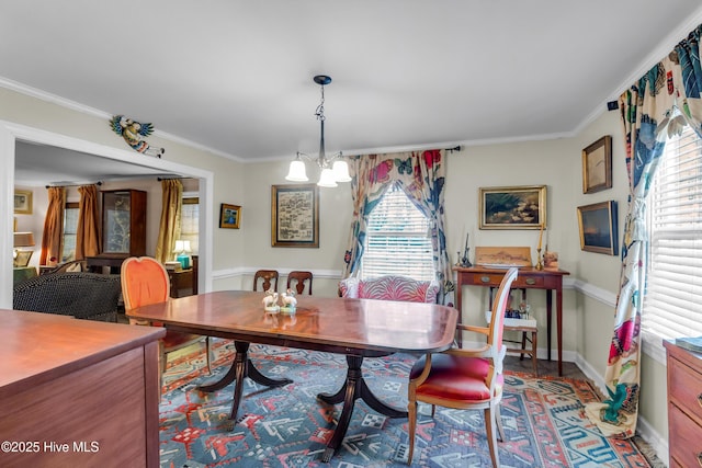 dining room with a chandelier, baseboards, and crown molding