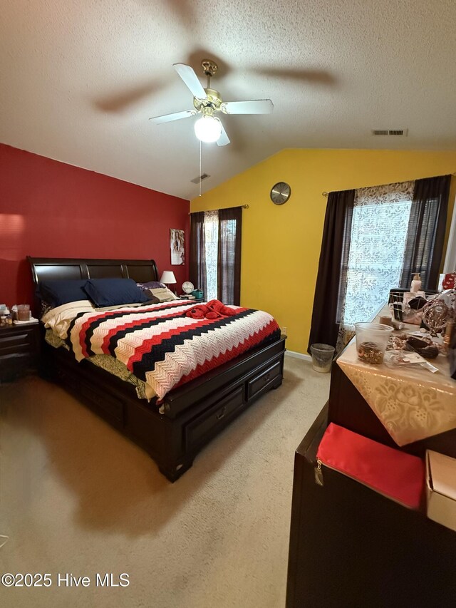 bedroom with light carpet, vaulted ceiling, a textured ceiling, and visible vents