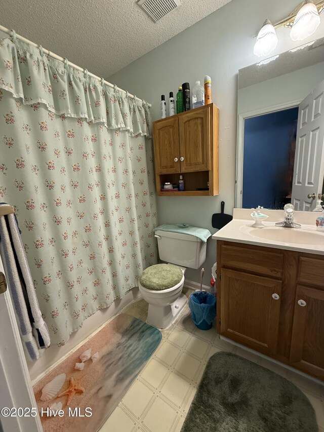 bathroom with visible vents, vanity, toilet, a textured ceiling, and tile patterned floors