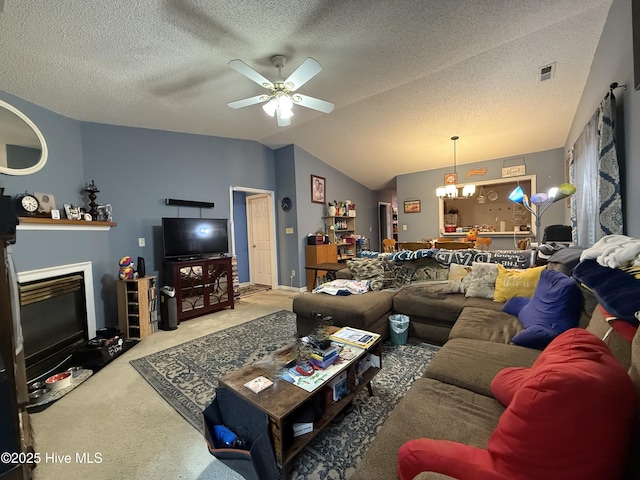carpeted living room with ceiling fan, a textured ceiling, visible vents, a fireplace with flush hearth, and vaulted ceiling