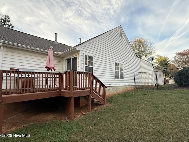 back of house featuring a yard, a deck, fence, and a shingled roof