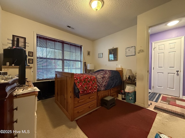 bedroom featuring light colored carpet, a textured ceiling, and visible vents