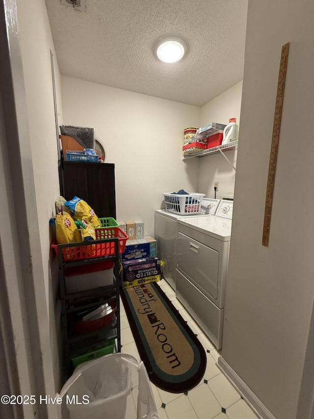 clothes washing area with laundry area, a textured ceiling, washing machine and dryer, and visible vents