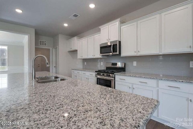 kitchen with white cabinets, stainless steel appliances, visible vents, and a sink