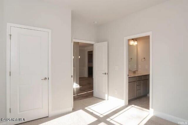 unfurnished bedroom featuring baseboards and ensuite bathroom
