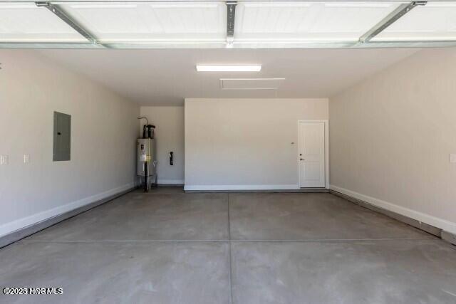 garage featuring baseboards, water heater, and electric panel
