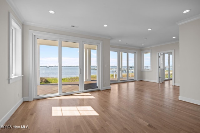 unfurnished living room with baseboards, crown molding, and a water view