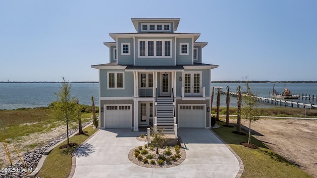 coastal home with concrete driveway, a water view, an attached garage, a porch, and stairs