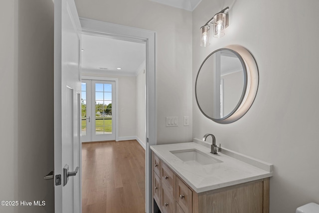 half bath featuring baseboards, wood finished floors, and vanity