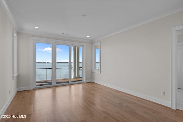 spare room featuring baseboards, crown molding, wood finished floors, and a water view
