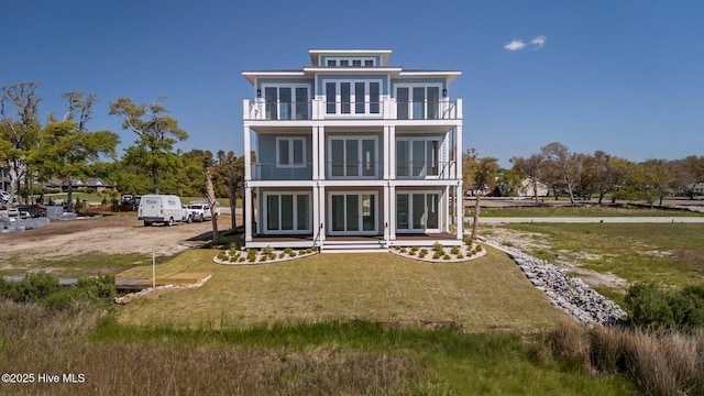 rear view of house with a lawn, a balcony, and french doors