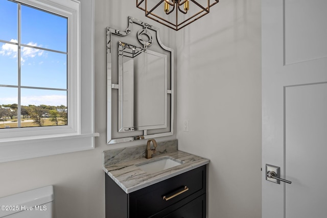 bathroom with vanity, a chandelier, and toilet