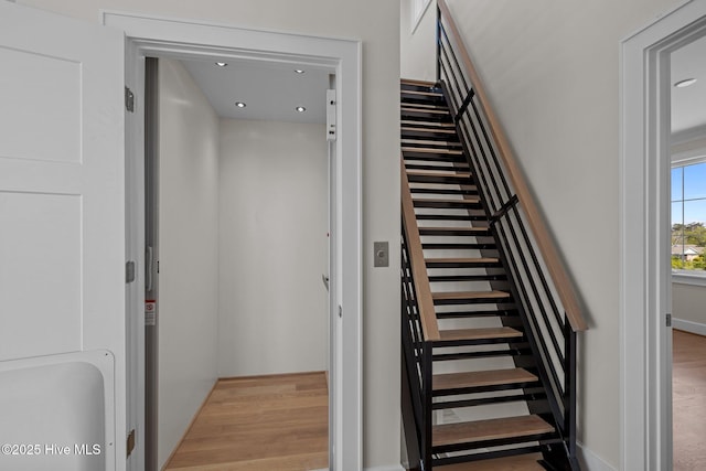 staircase featuring wood finished floors, elevator, a sauna, baseboards, and recessed lighting