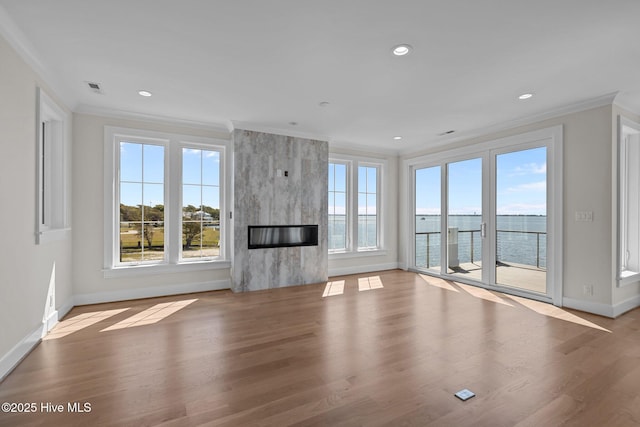 unfurnished living room featuring baseboards, a fireplace, a healthy amount of sunlight, and crown molding