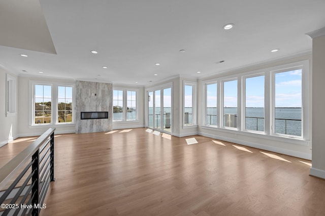 unfurnished living room with baseboards, wood finished floors, recessed lighting, and a water view