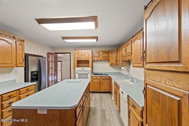kitchen featuring a sink, light wood-style flooring, white appliances, and brown cabinets