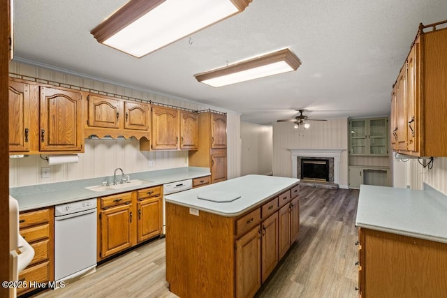 kitchen with brown cabinetry, white dishwasher, a sink, and light wood finished floors