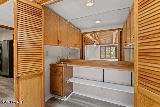 kitchen featuring a sink, freestanding refrigerator, a ceiling fan, recessed lighting, and wood finished floors