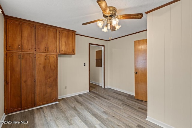 unfurnished bedroom with crown molding, light wood-style flooring, ceiling fan, and baseboards