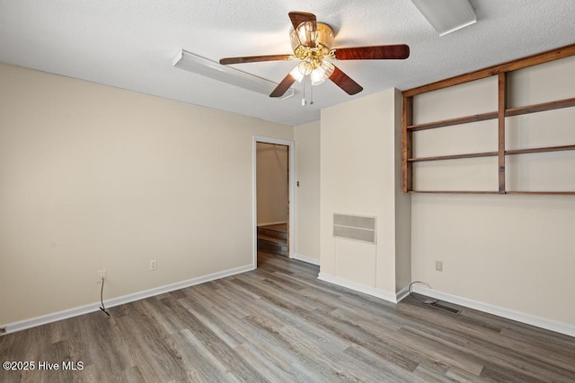 empty room with visible vents, ceiling fan, baseboards, and wood finished floors