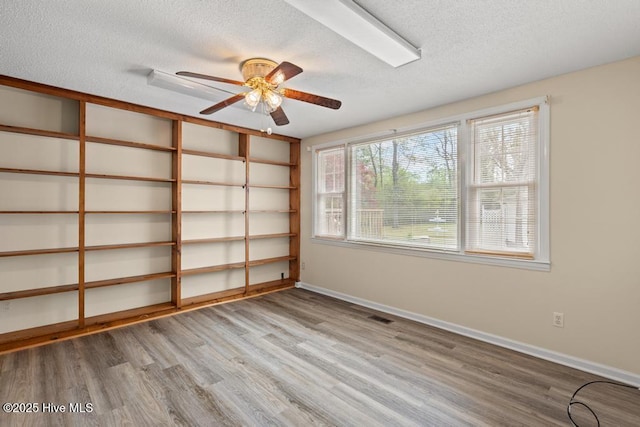 spare room featuring visible vents, ceiling fan, wood finished floors, and a textured ceiling