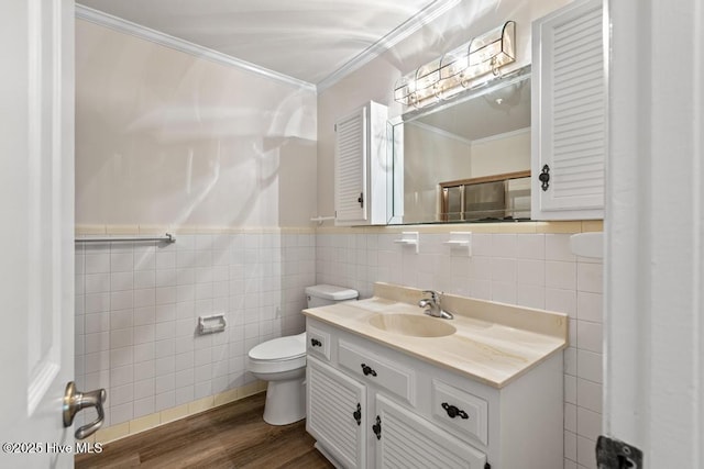 bathroom with vanity, ornamental molding, toilet, wood finished floors, and tile walls