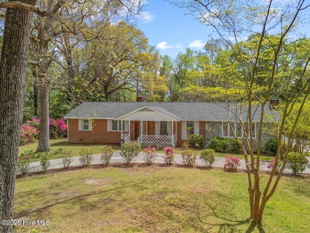 ranch-style house with a porch, a chimney, a front yard, and brick siding