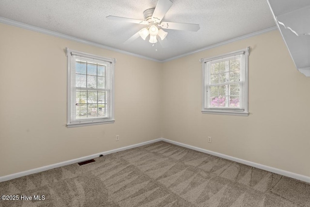 carpeted empty room featuring ornamental molding, visible vents, a wealth of natural light, and baseboards