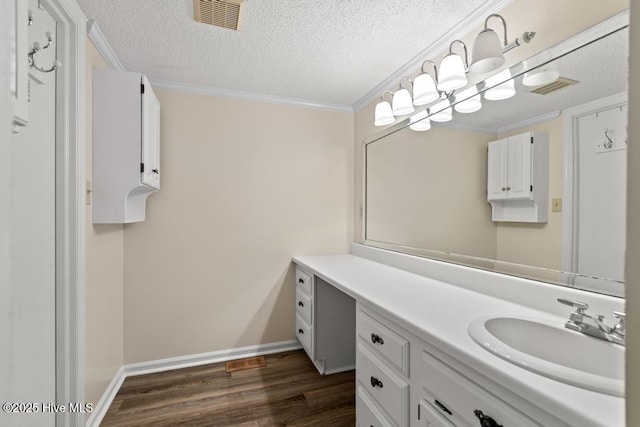 bathroom featuring visible vents, ornamental molding, a textured ceiling, vanity, and wood finished floors