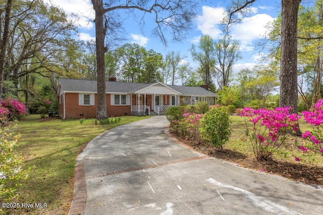 ranch-style home featuring aphalt driveway, crawl space, a front yard, brick siding, and a chimney