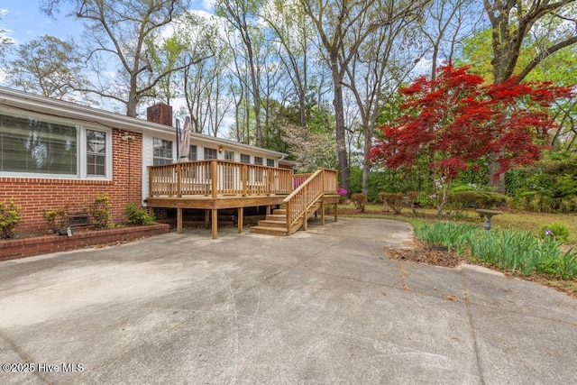 exterior space with brick siding, a deck, and a chimney
