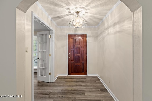 entrance foyer featuring baseboards, arched walkways, an inviting chandelier, and dark wood-style floors