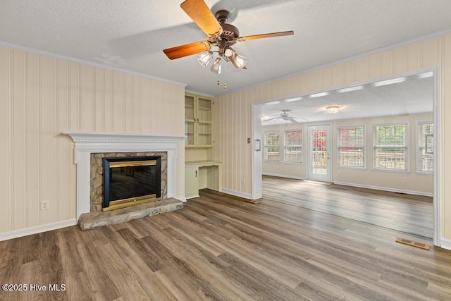 unfurnished living room featuring crown molding, ceiling fan, visible vents, wood finished floors, and baseboards