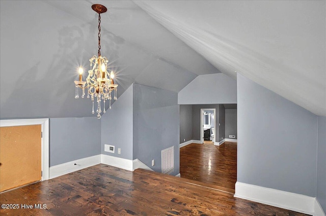 additional living space with a chandelier, lofted ceiling, visible vents, baseboards, and wood finished floors