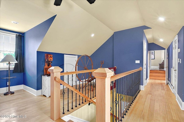 hallway featuring an upstairs landing, wood finished floors, vaulted ceiling, and baseboards