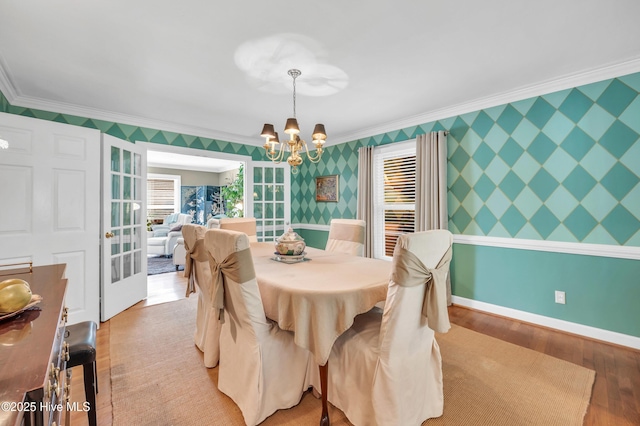 dining room with crown molding, a chandelier, light wood-type flooring, wallpapered walls, and baseboards
