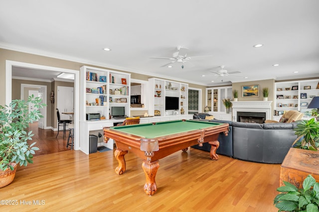 playroom featuring recessed lighting, light wood-style floors, ornamental molding, a fireplace, and a ceiling fan