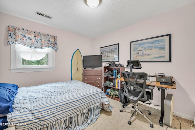 carpeted bedroom featuring a textured ceiling, an office area, and baseboards