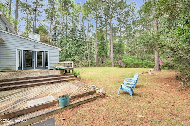 view of green lawn with a wooden deck and french doors