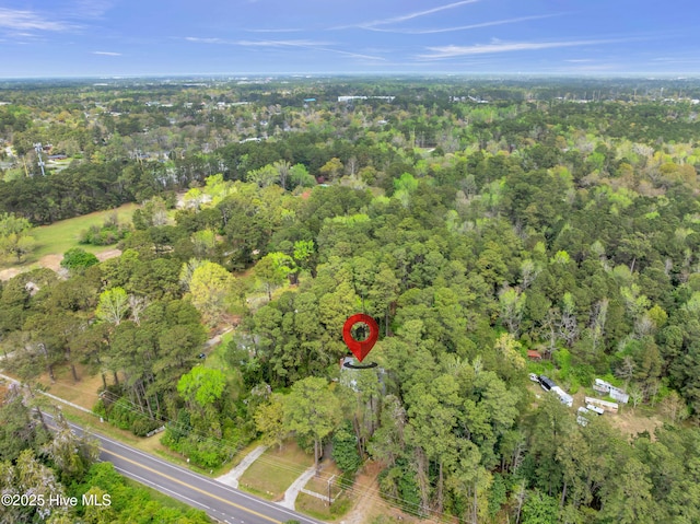 aerial view of property and surrounding area featuring a heavily wooded area