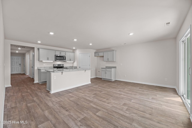 409 King Creek Dr, Havelock, NC 28532 - kitchen featuring appliances with stainless steel finishes, recessed lighting, light wood finished floors, a kitchen island with sink, and gray cabinets
