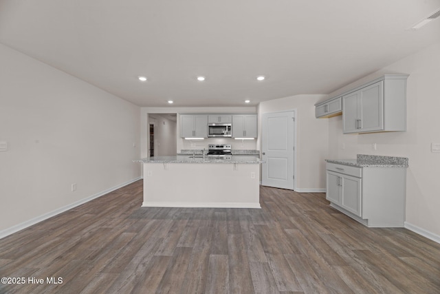 409 King Creek Dr, Havelock, NC 28532 - kitchen featuring appliances with stainless steel finishes, recessed lighting, dark wood finished floors, an island with sink, and light stone countertops
