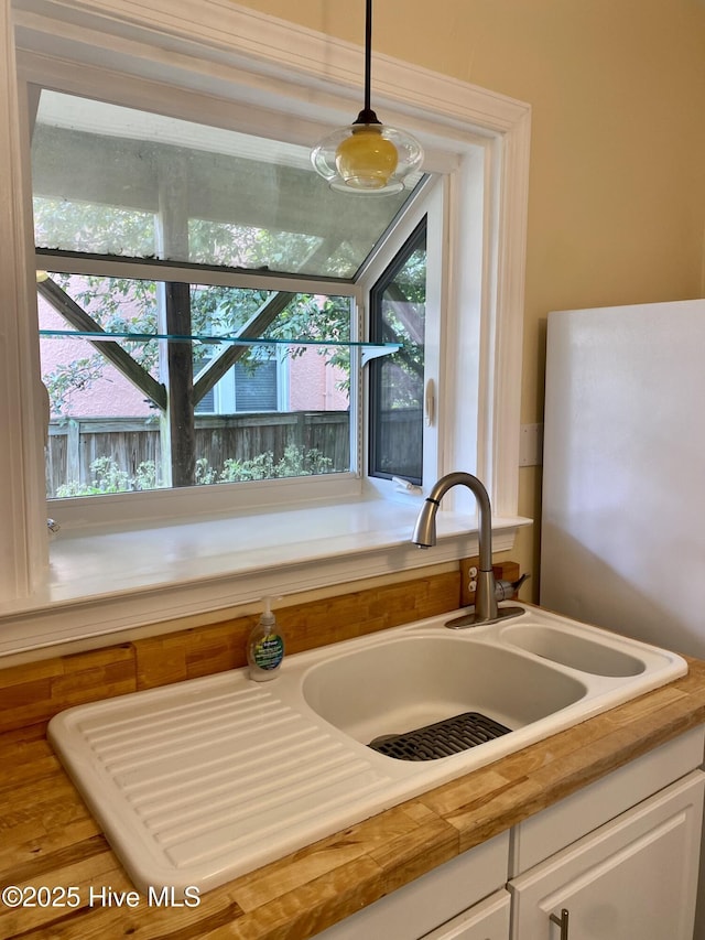 interior details featuring a sink, hanging light fixtures, white cabinets, and light countertops