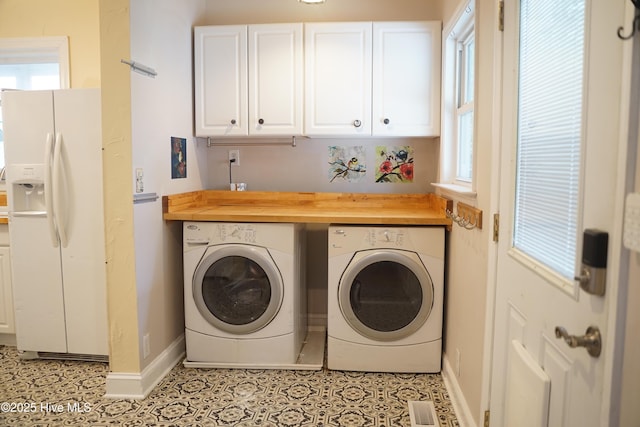 washroom featuring baseboards, visible vents, cabinet space, and washer and clothes dryer