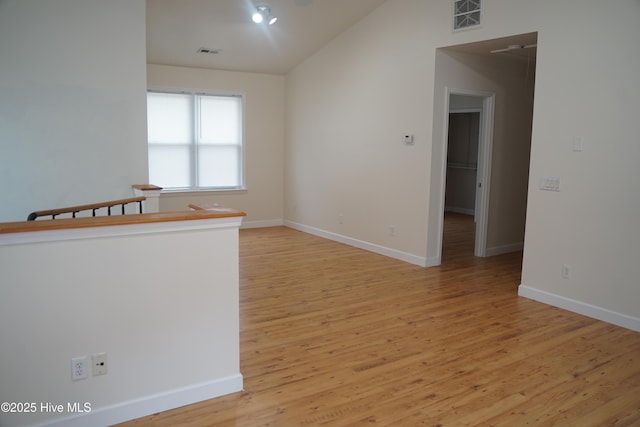 spare room with baseboards, visible vents, vaulted ceiling, and light wood-type flooring